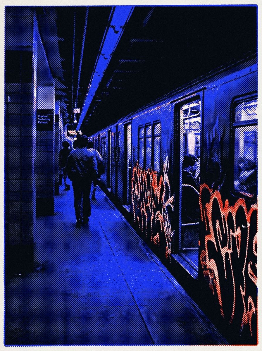 A New York subway platform at night, a train with red graffiti standing with its doors open